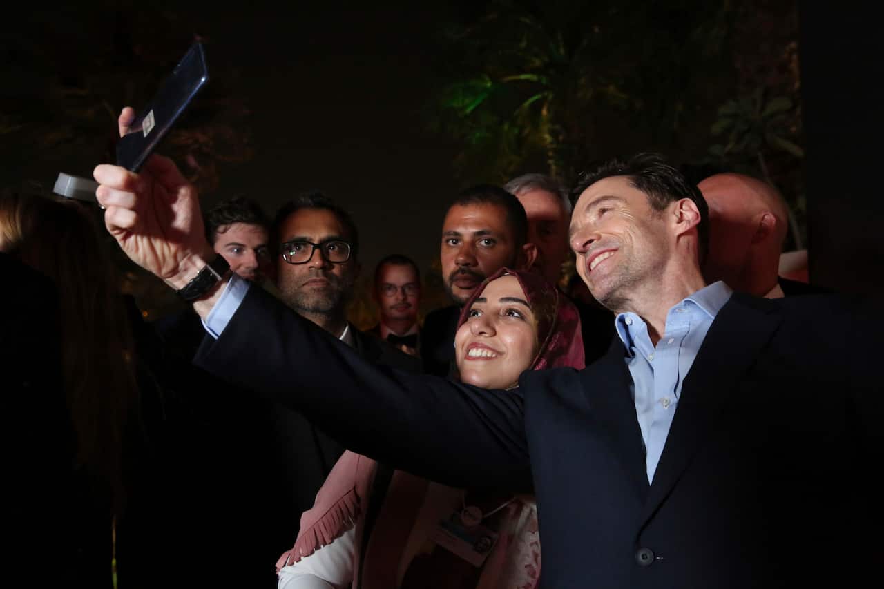 Actor Hugh Jackman takes a mobile phone photograph with a fan.