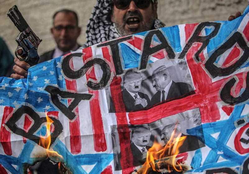 Palestinians burn defaced photos of the Israeli and US presidents during a protest in Gaza City, 25 March 2019.