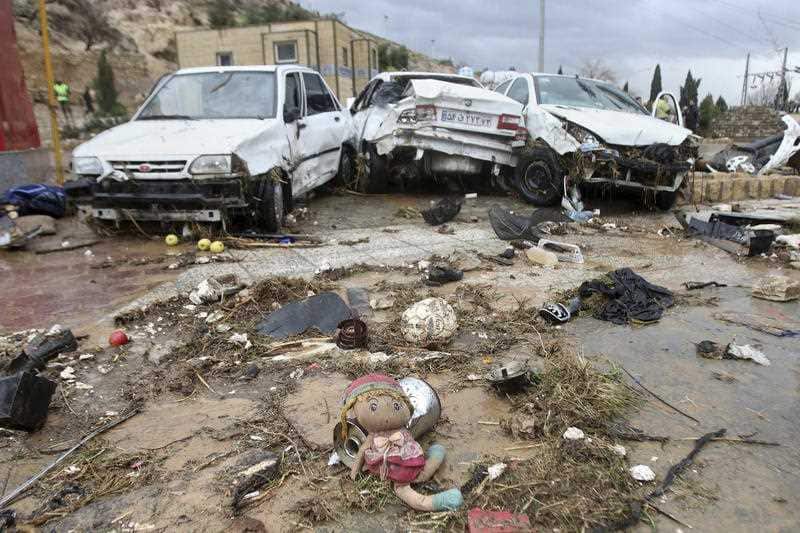 A child's doll lies in front of destroyed cars after a flash flood in the southern city of Shiraz, Iran.