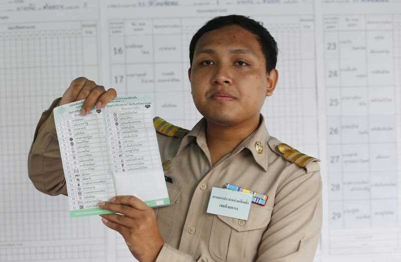An officer counts ballots in the general election after closing a polling station in Bangkok, Thailand. 