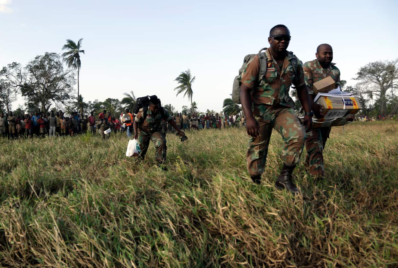 Members of the South African Defence Forces Medics walk towards their helicopter after assisting a community affected by the cyclone.