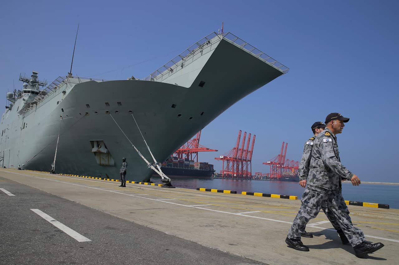 Australian naval officers walk next to the HMAS Canberra.