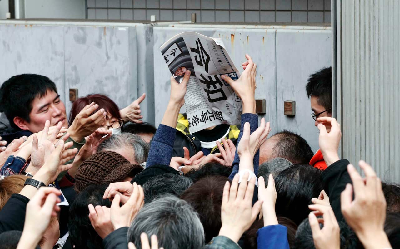 People try to grab an extra edition of a newspaper reporting Japan's new era name Reiwa.
