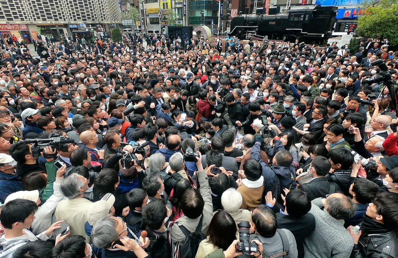 People crowd to get a copy of newspaper extra edition reporting the name of new era in Tokyo Monday, April 1, 2019. The name of the era of Japan's soon-to-be-emperor Naruhito will be "Reiwa," the government announced Monday. (Kyodo News via AP)