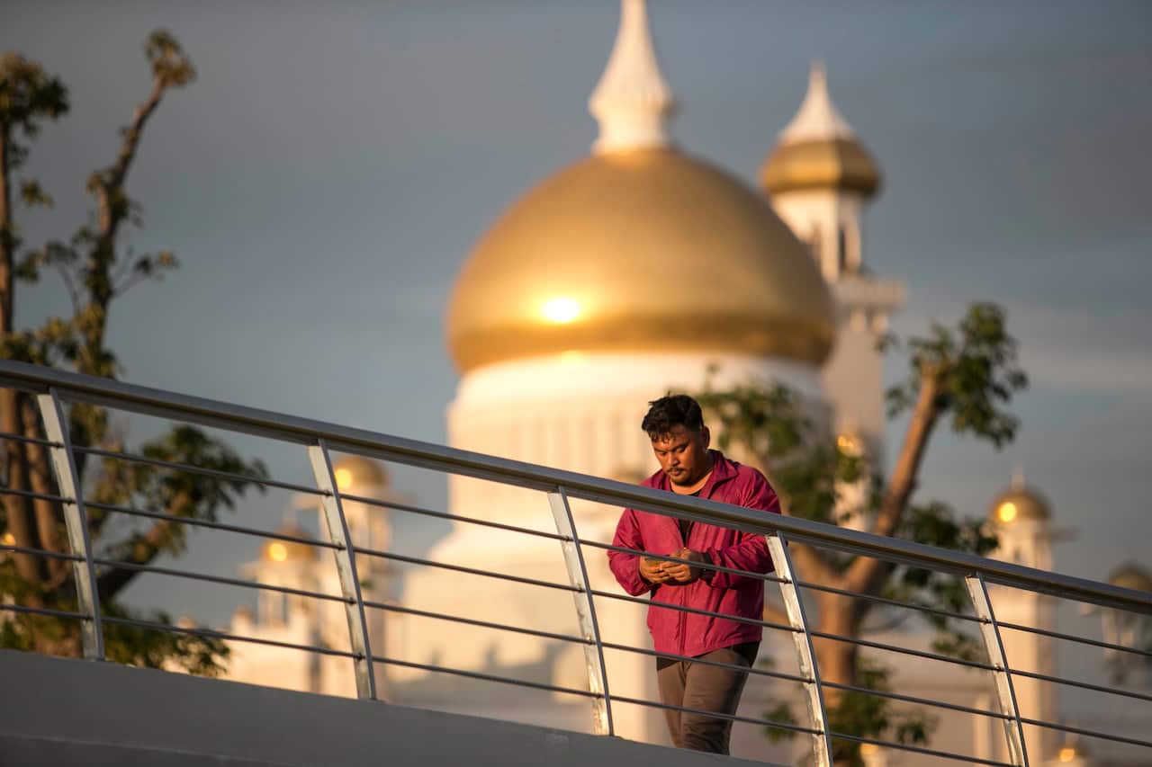 A man walks past the Sultan Omar Ali Saifuddien mosque while doing his afternoon exercise at Taman Mahkota Jubli Emas park, in Bandar Seri Begawan, Brunei.