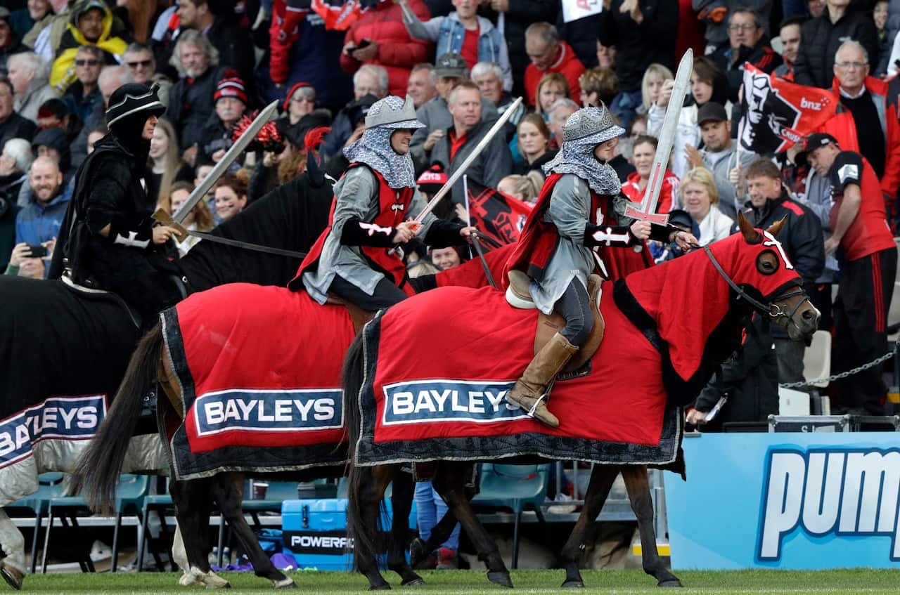 Sword-wielding knights ride around the arena of a Crusaders game. 