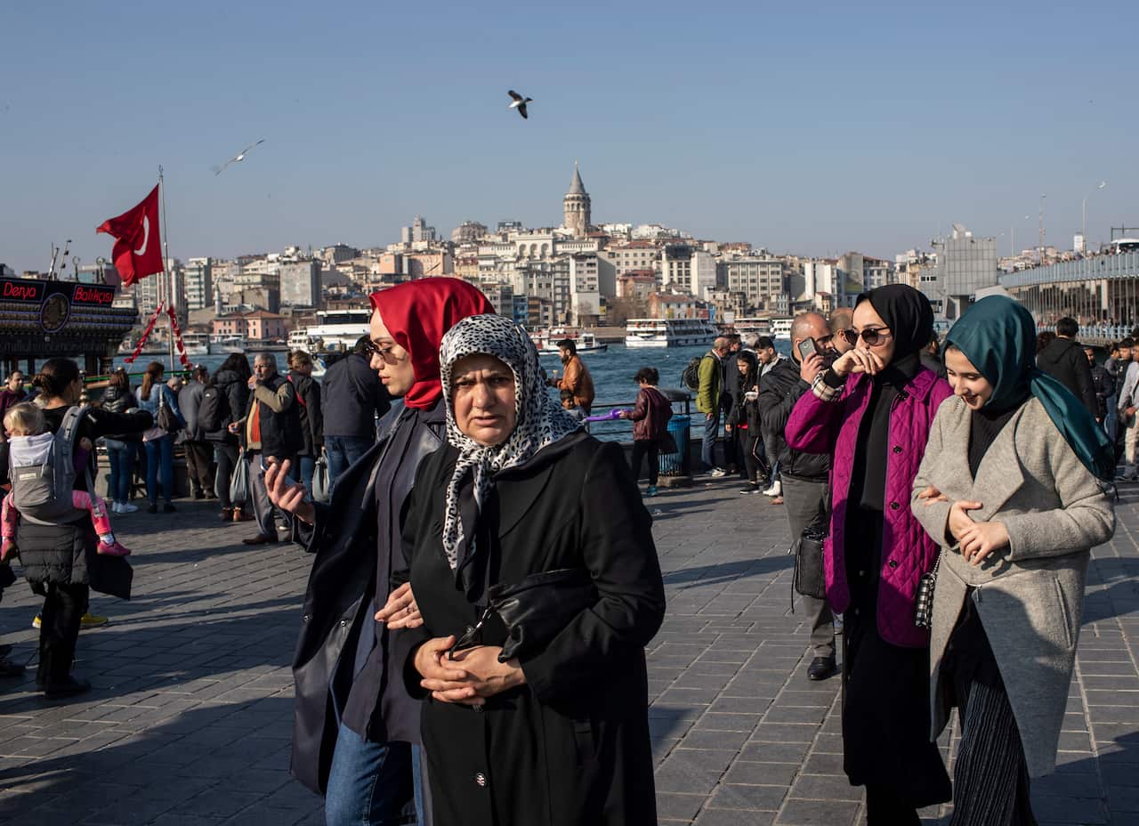 People at Eminonu Square, with Galata Tower seen in the background, on a sunny day in Istanbul, Turkey.