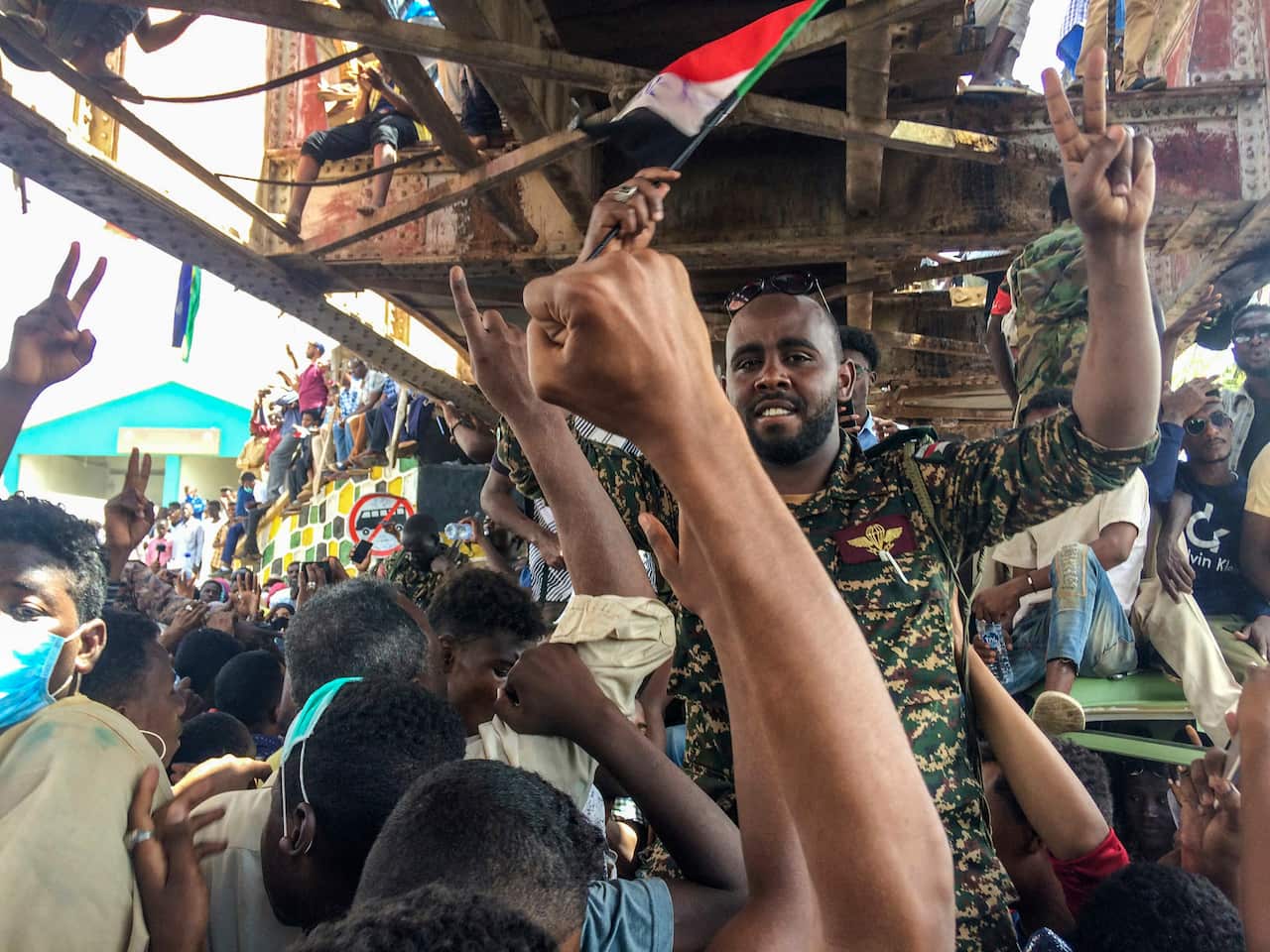 A Sudanese soldier protects protesters at a demonstration near the military headquarters, in the capital Khartoum, Sudan. 