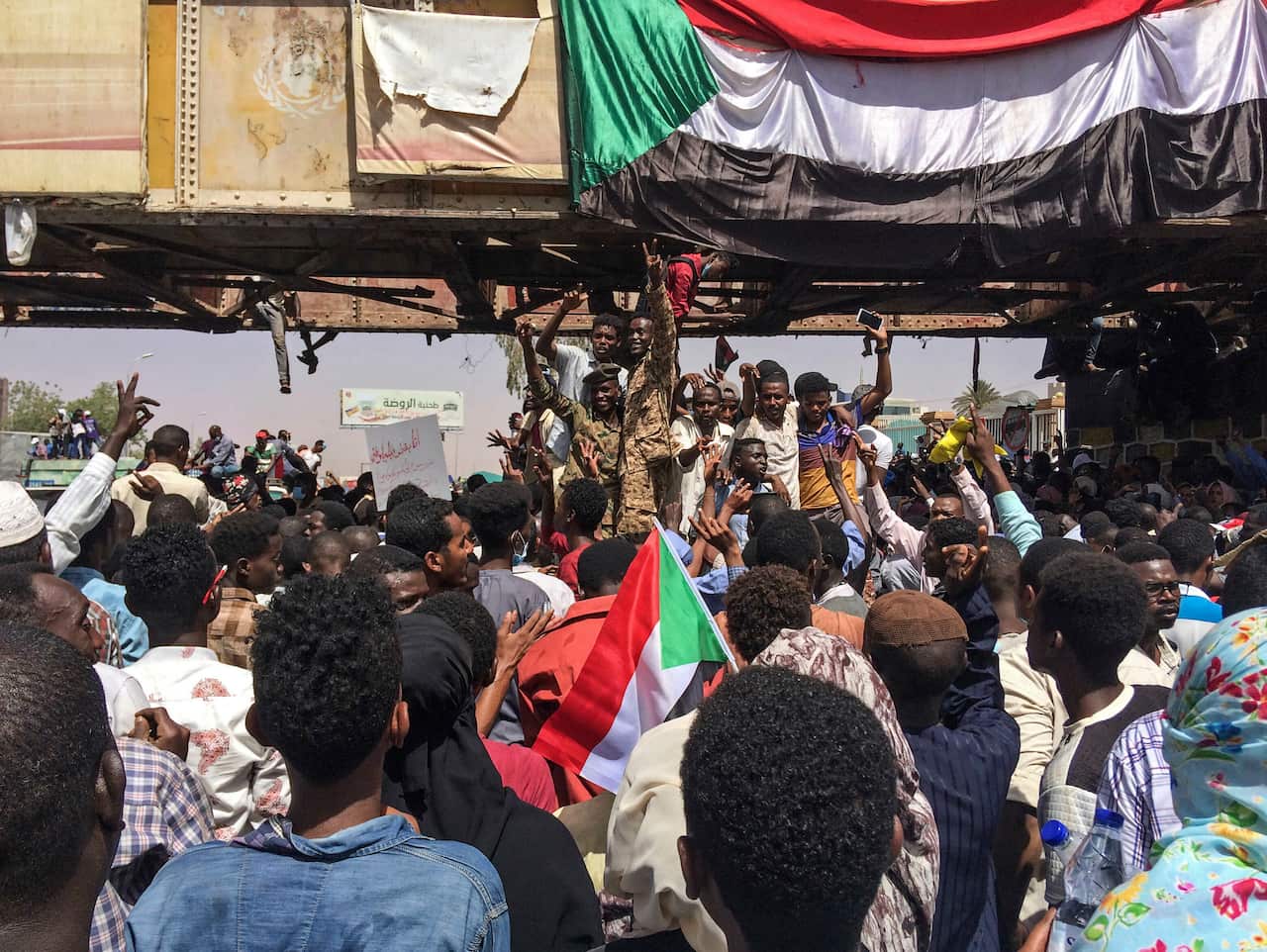 Uniformed Sudanese soldiers flash the victory sign as they stand among protesters at a demonstration in the capital Khartoum, Sudan. 