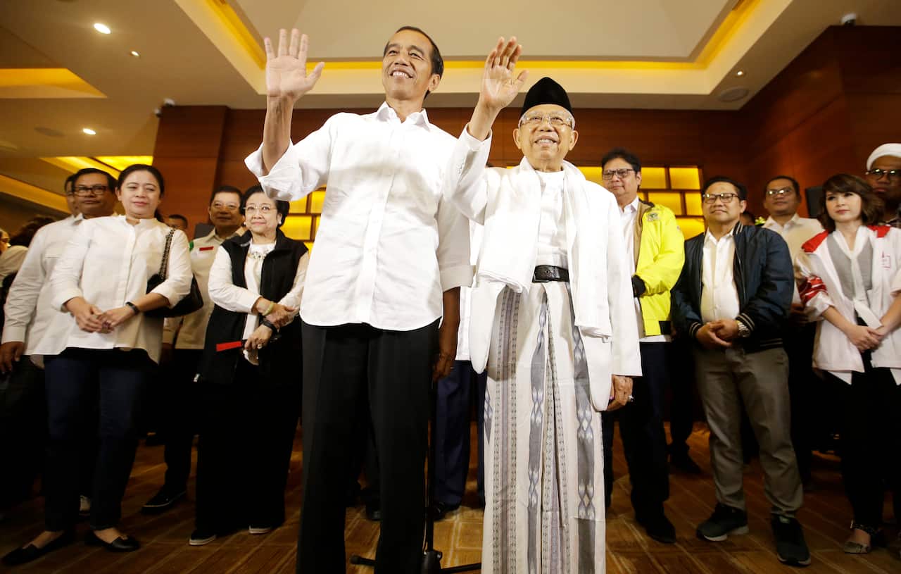 Indonesian President Joko Widodo and his running mate Ma'ruf Amin, right, wave to journalist  after a press conference in Jakarta, Indonesia.