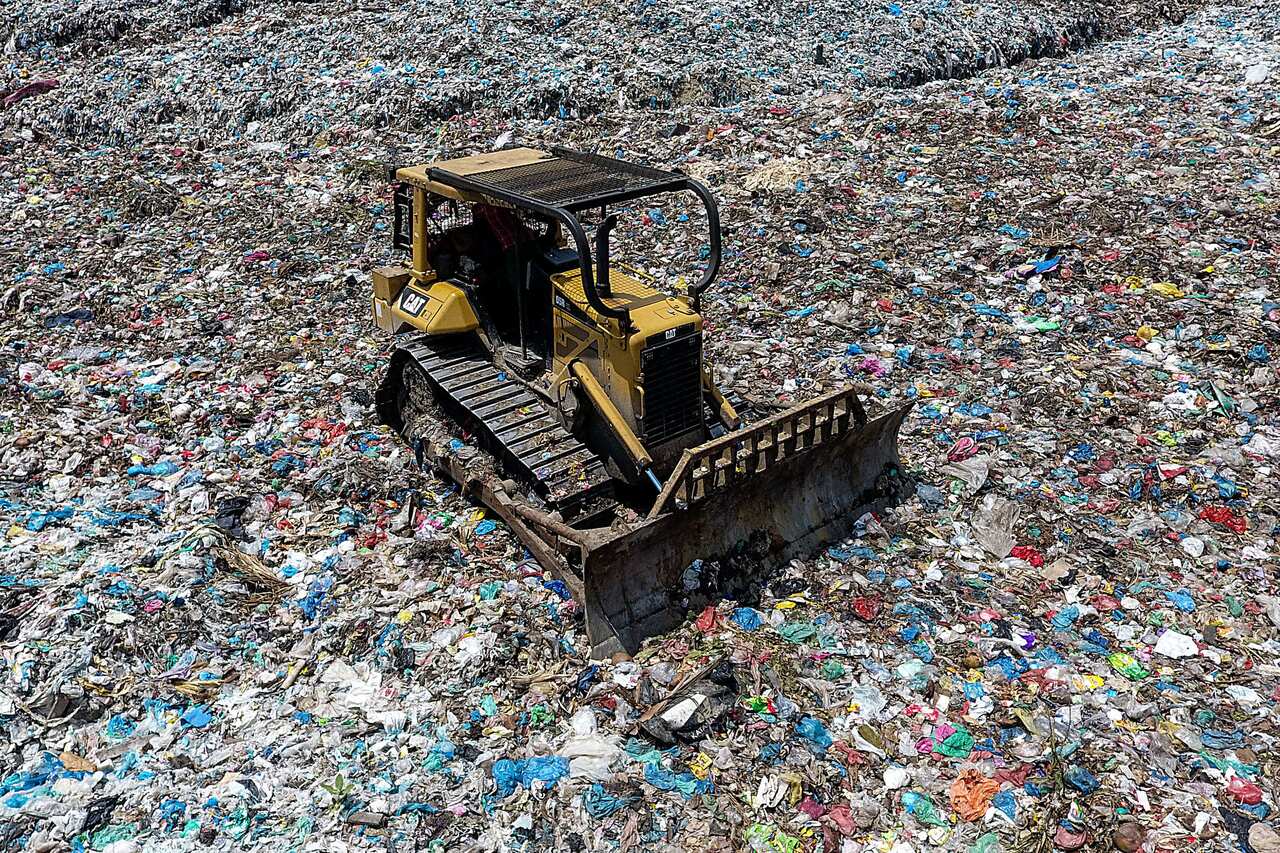 A bulldozer seen working to move piles of waste at a garbage dumps in Lhokseumawe, Aceh province, Indonesia.