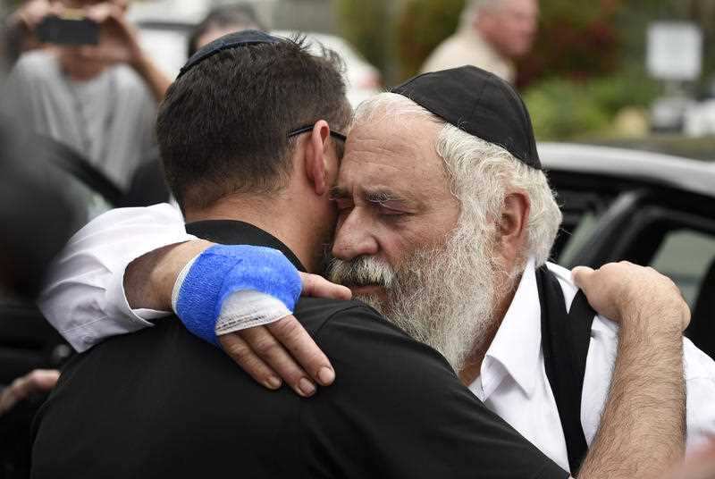 Rabbi Yisroel Goldstein (right) comforts a worshipper outside the Chabad of Poway synagogue in California following a mid-worship shooting.,