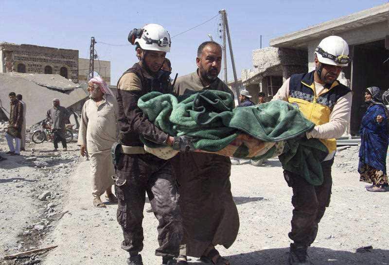Syrian Civil Defence workers carrying a victim after a deadly airstrike hit a market killing several people in Idlib, Syria. 