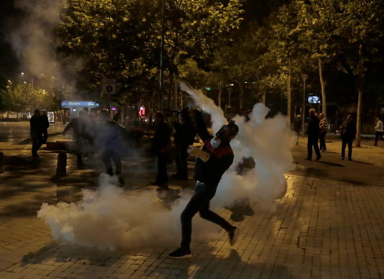 A supporter of the opposition throws back a tear gas cannister to riot police during a protest in Tirana in Albania.