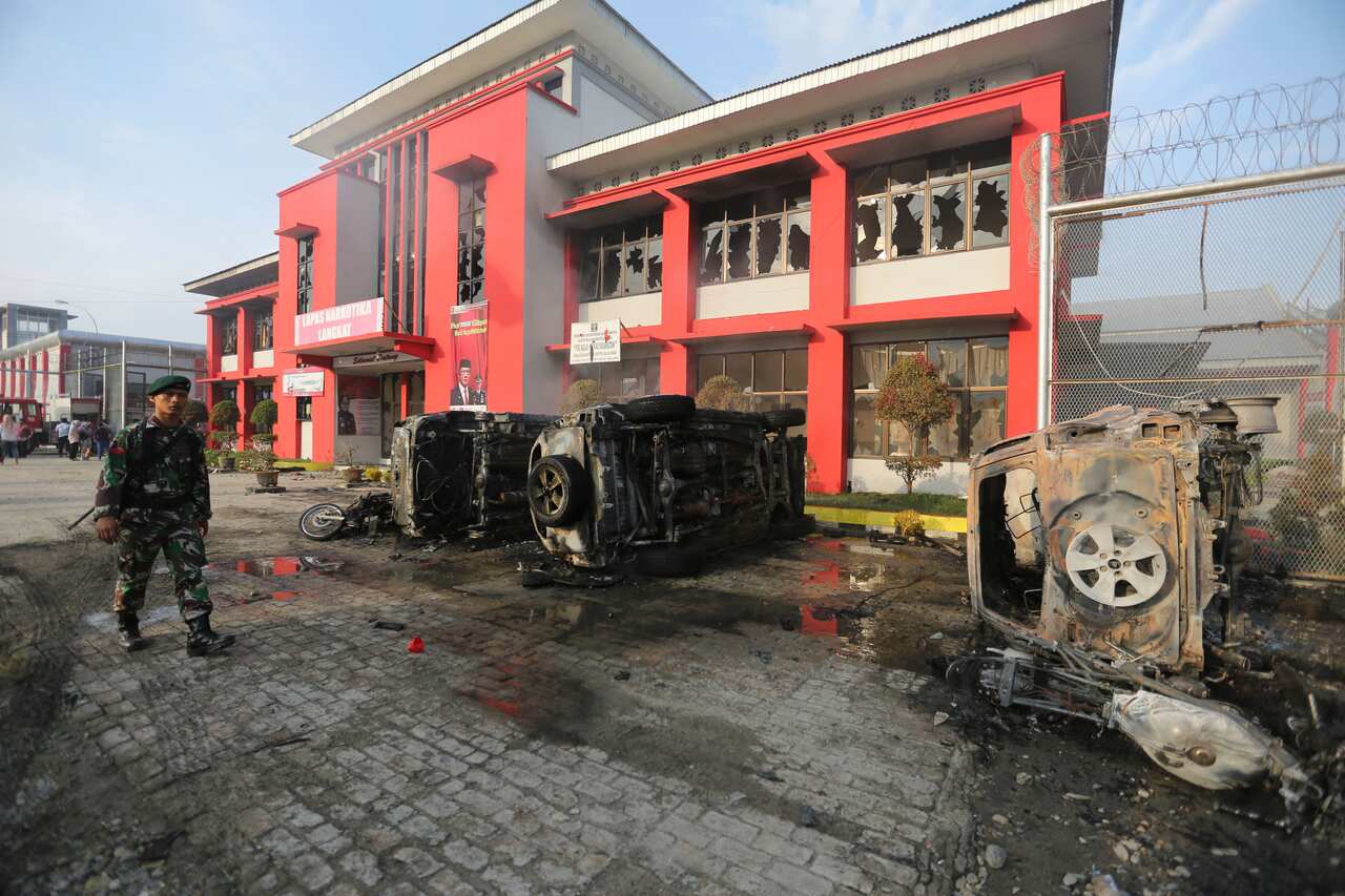 An Indonesian soldier walks past wreckage of burnt cars following a prison riot at Langkat Prison in Langkat, North Sumatra, Indonesia.