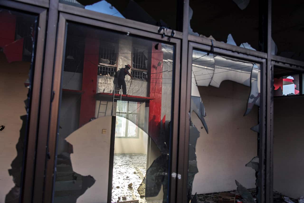 A fireman extinguishes a fire reflected on a broken window.
