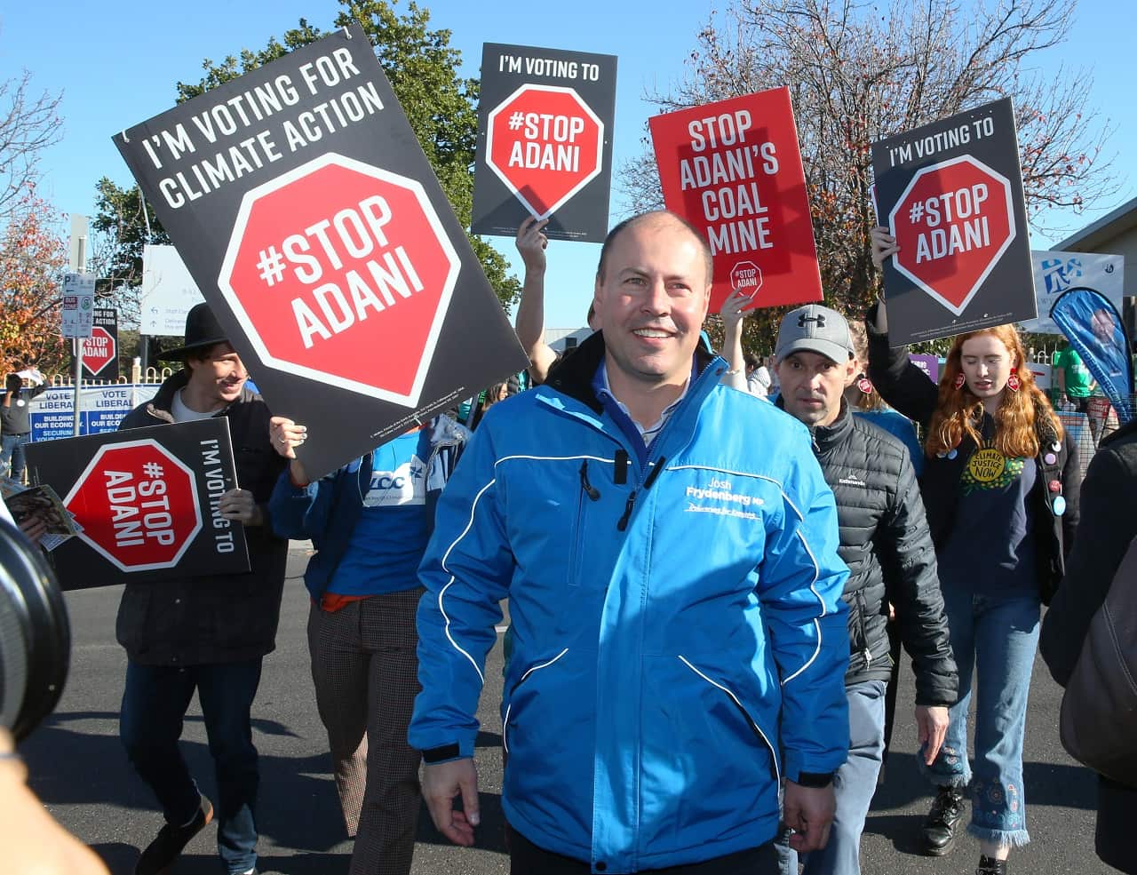 Treasurer Josh Frydenberg is followed by anti Adani protesters.