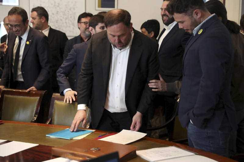 Oriol Junqueras, centre, prepares to sign some documents and collect his credentials.