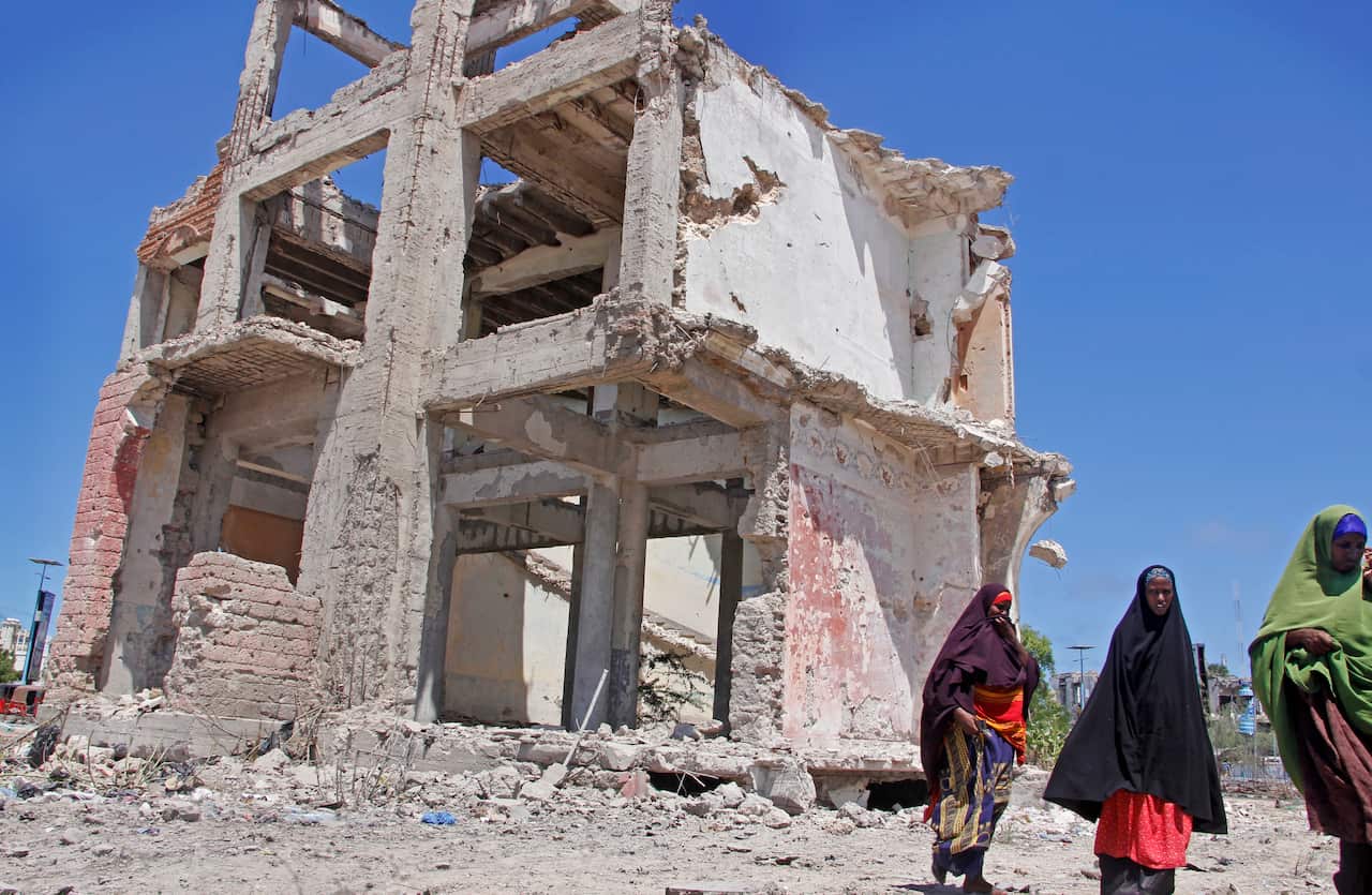 Somali women walk past a destroyed building after a suicide car bomb attack in the capital Mogadishu.
