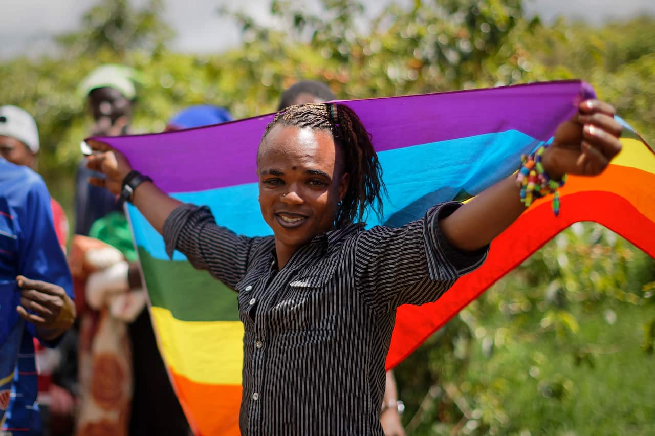 LGBT refugee from Congo, stands with a rainbow flag at a protest against their treatment by authorities.