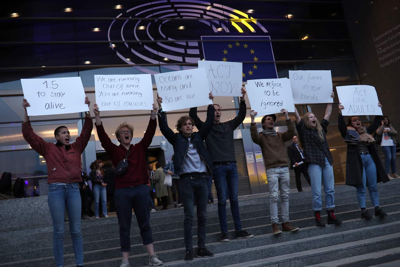 Climate activists hold up placards outside the European Parliament during the EU elections. 