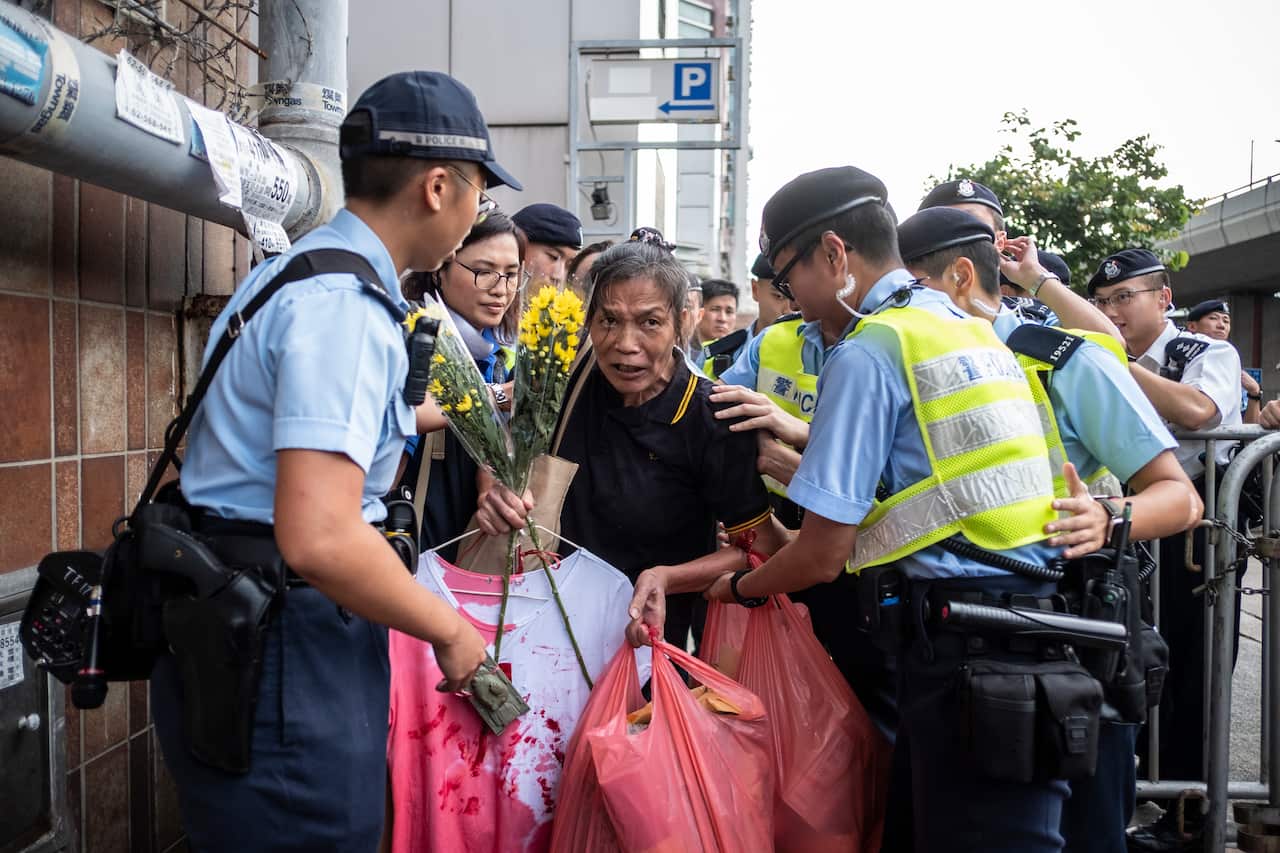 Pro-democracy participant seen with flowers forcing her way through the police.