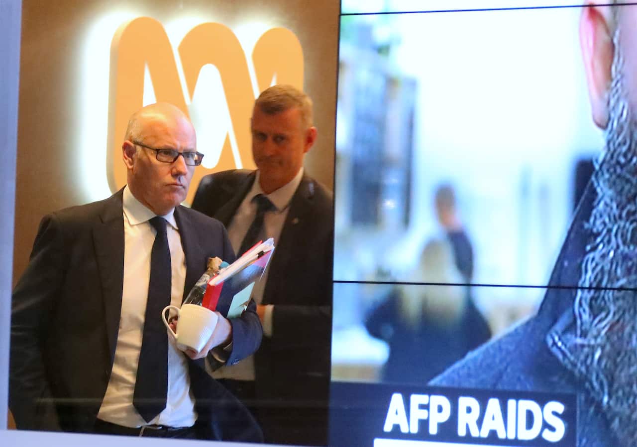 John Lyons (left), Executive Editor of the ABC News, is followed by an Australian Federal Police officer as they walk out the main entrance to the ABC building located at Ultimo in Sydney, Wednesday, June 5, 2019. (AAP Image/David Gray) NO ARCHIVING