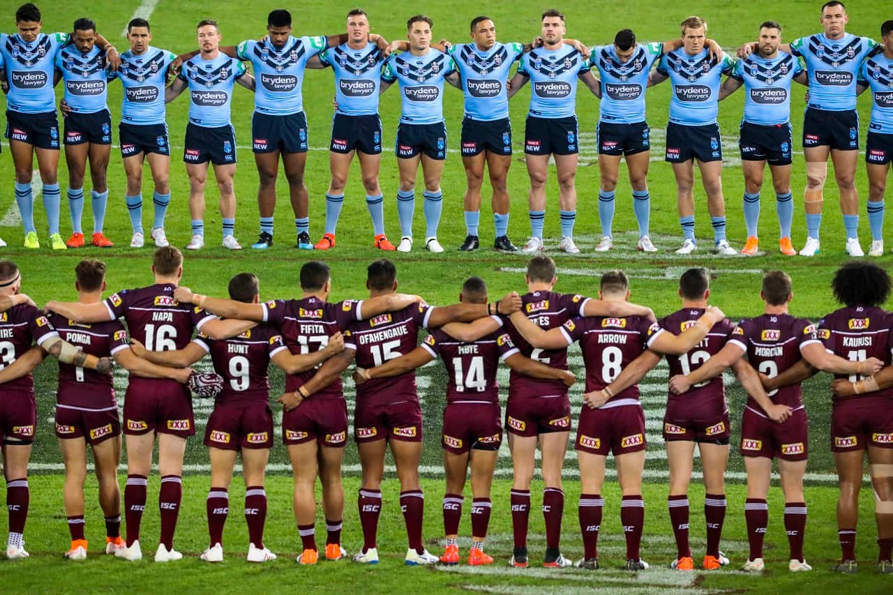 Maroons and Blues players line up for the national anthem.