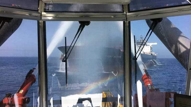 The crude oil tanker Front Altair seen through glass observation window as water cannons operate