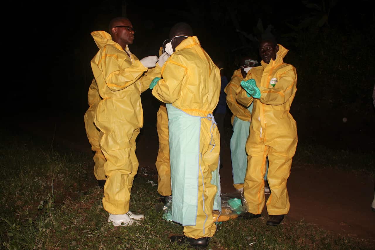 Health workers prepare to transport the body of awoman who died of Ebola to the burial site in a border town close to Democratic Republic of the Congo
