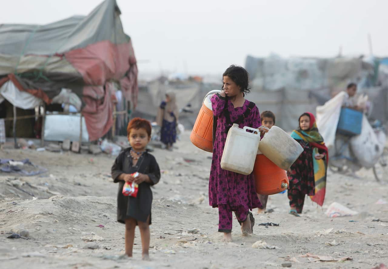 Afghan refugees who fled their homeland due to war and famine, on their way to collect clean water in slums of Lahore, Pakistan.