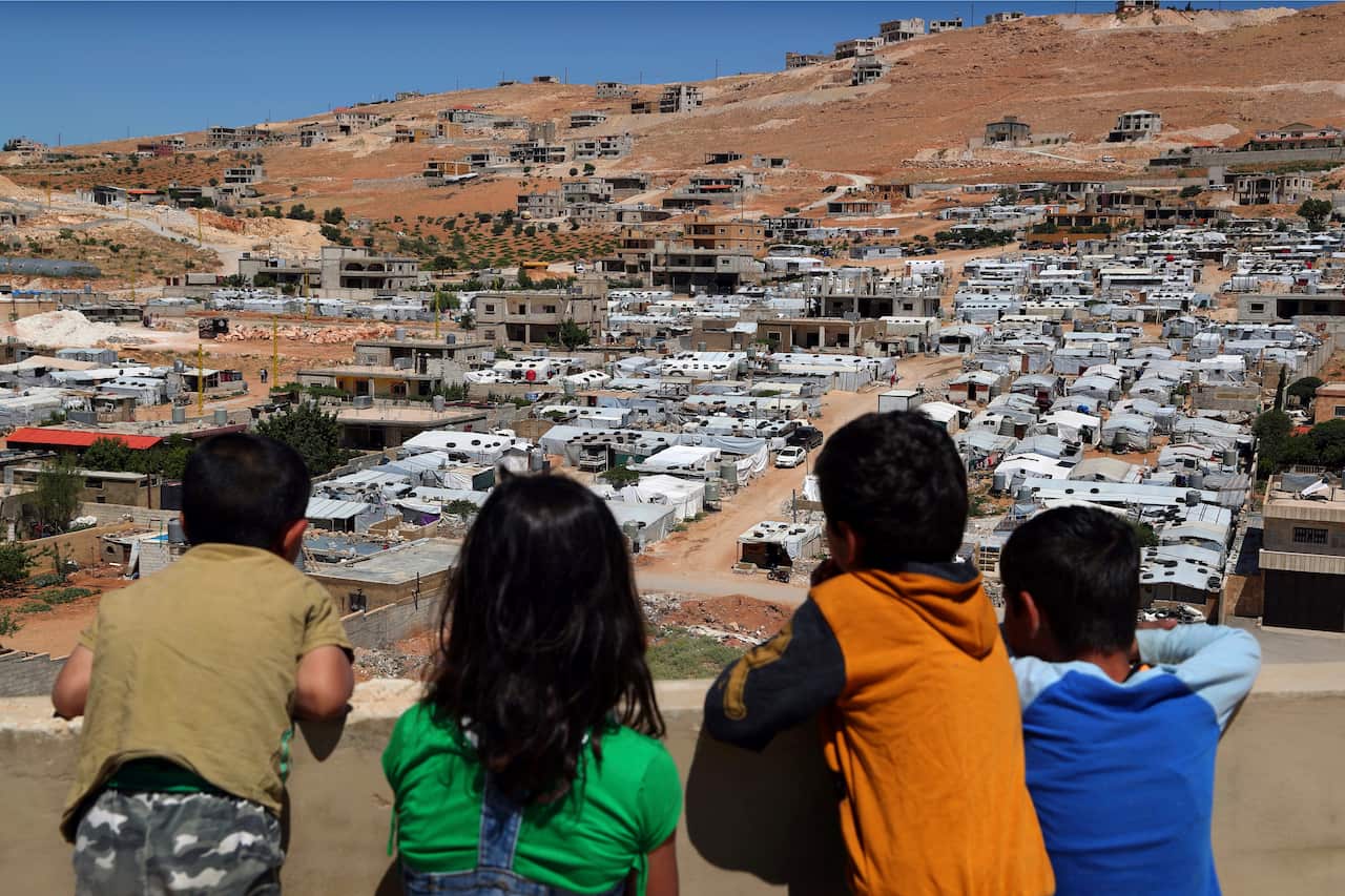 Lebanese children look from the rooftop of their home at a Syrian camp in the eastern Lebanese border town of Arsal, Lebanon.