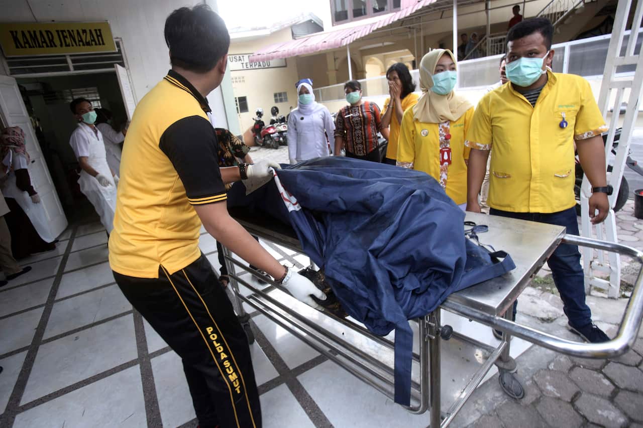 Paramedics put body bags containing the remains of the victims of a fire that razed through a match factory in Medan, North Sumatra, Indonesia.