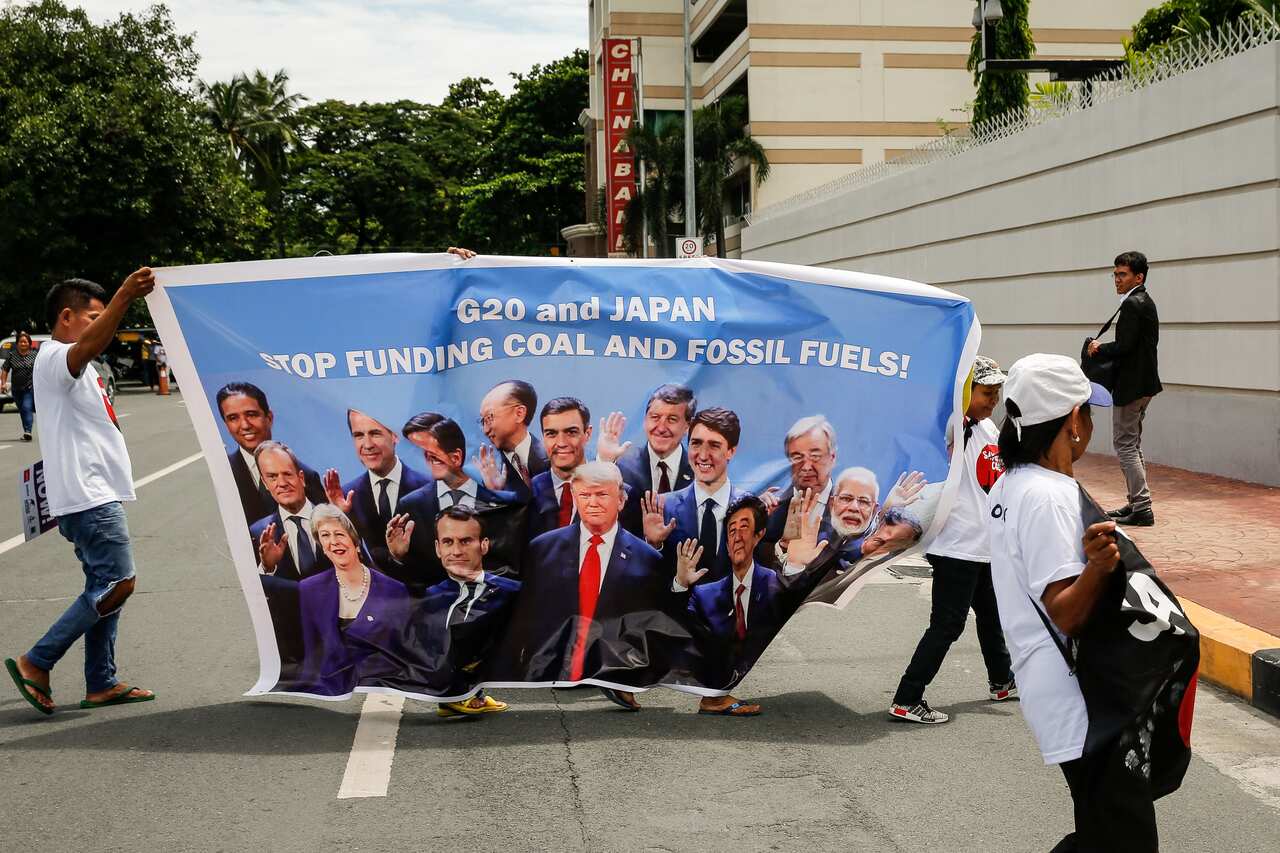 Anti-coal activists carry a banner with images of world leaders in front of the Japanese embassy in Manila, Philippines.
