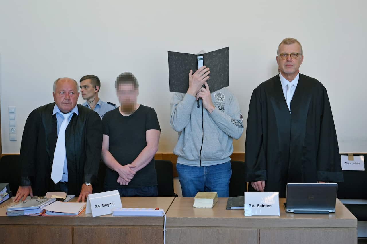 Andreas V. (2-R with his lawyer Johannes Salmen), 56, Mario S. (2-L with his lawyer Juergen Bogner), 34, and Heiko V. (not pictured), 49, arrive for the first day of their trial