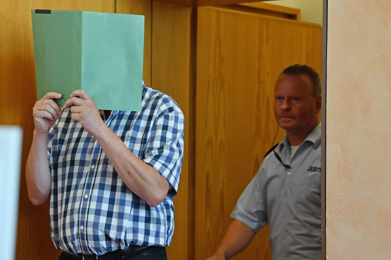 Andreas V. (not pictured), 56, Mario S. (not pictured), 34, and Heiko V. (L), 49, arrive for the first day of their trial.