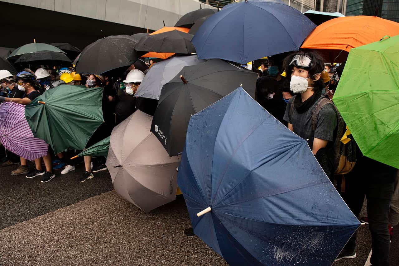 Anti government protesters using umbrellas as shields.