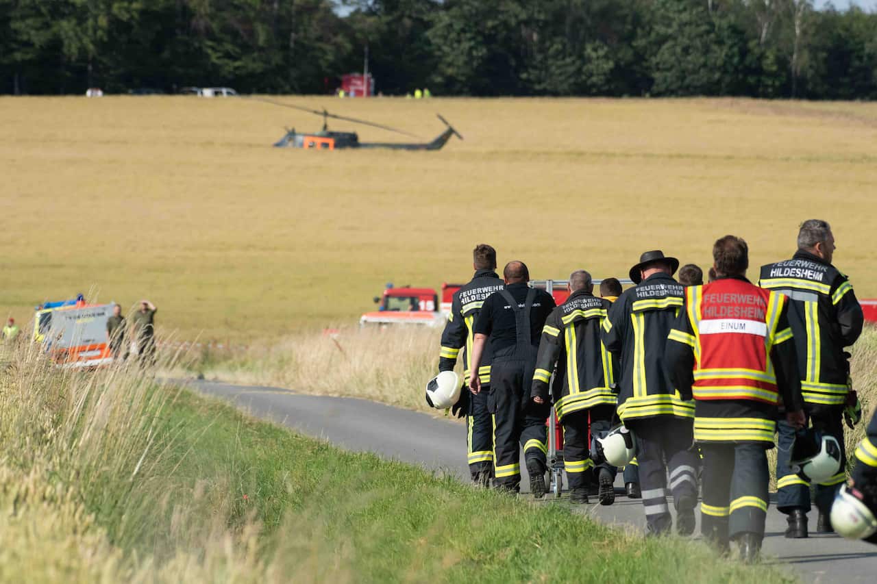 Firefighters walk along a path to the crash site of a German Armed forces helicopter.
