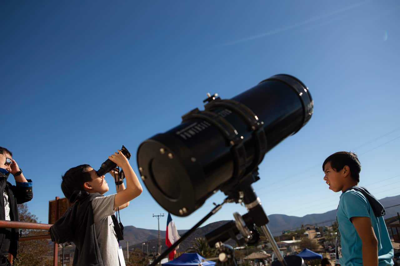 Children test out special binoculars to view tomorrow's total solar eclipse in La Higuera, Chile.