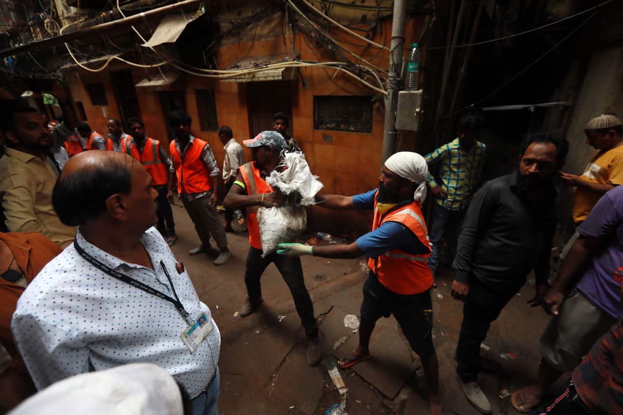 Municipal workers clear the debris from the site of collapsed building in Dongri area of Mumbai, India.
