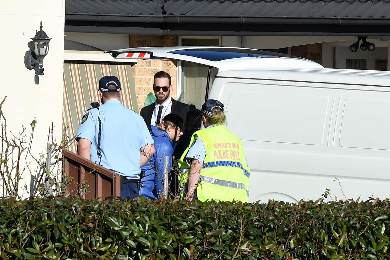 Forensic workers load a body into a van as NSW Police establish a crime scene at a home at St Clair in Sydney.