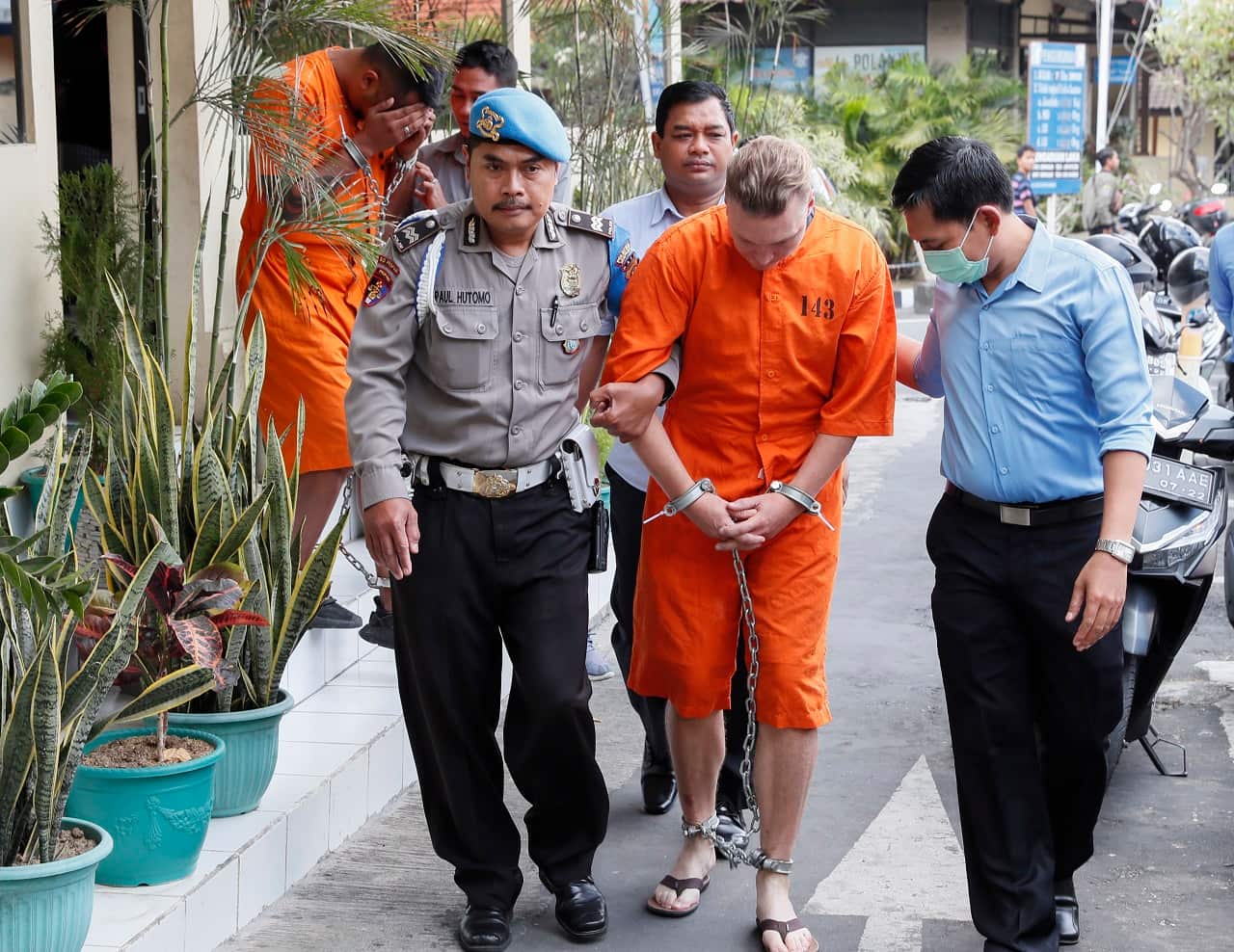 David Van Iersel and William Cabantog are escorted by police officers.