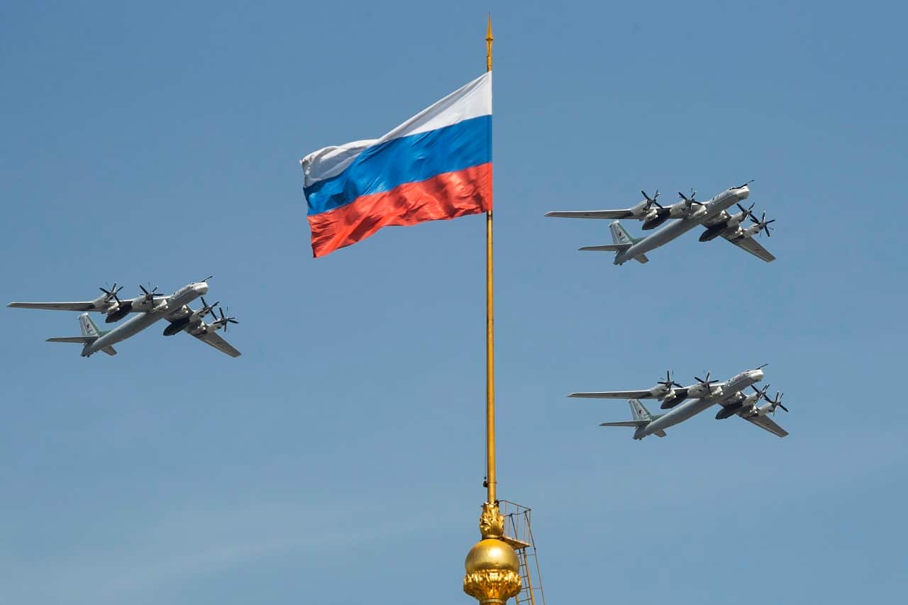 Russian Tu-95 strategic bombers fly past the Russian flag on the Kremlin complex.