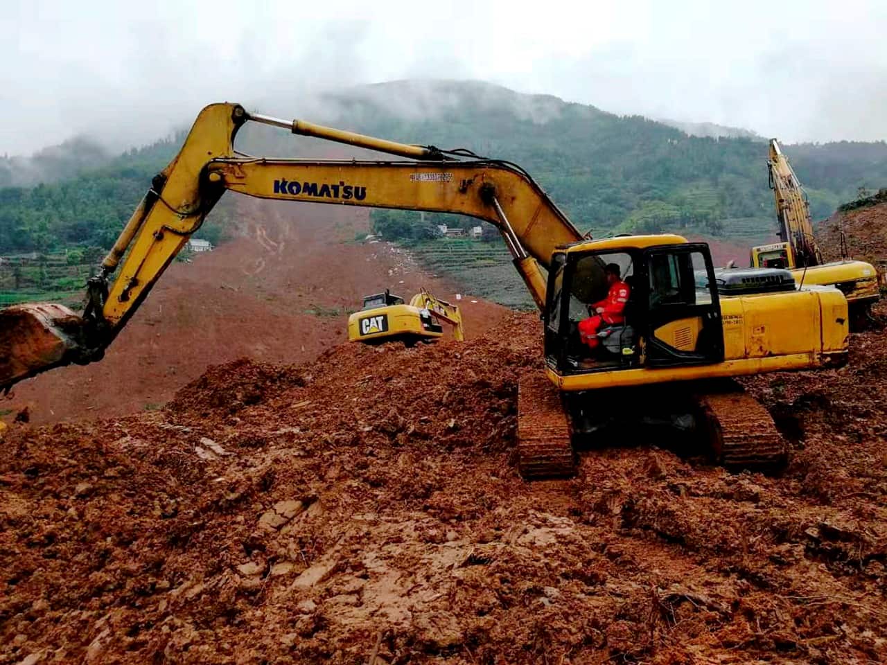 An excavator digs in debris of a landslide.