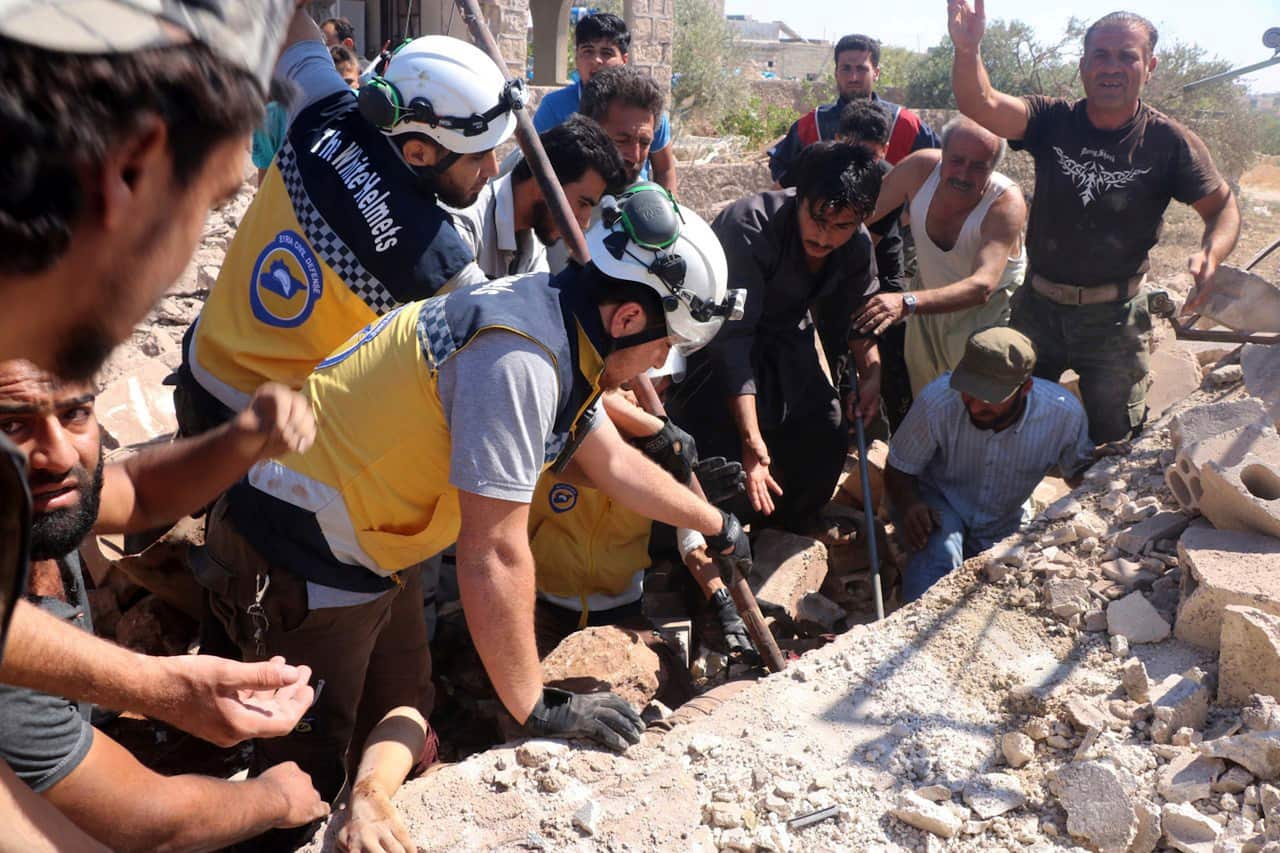 Humanitarian workers search for victims under the rubble of a destroyed building hit by airstrikes in Syria.