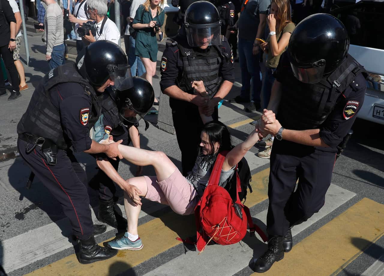 Police officers detain a woman during an unsanctioned rally in the center of Moscow.