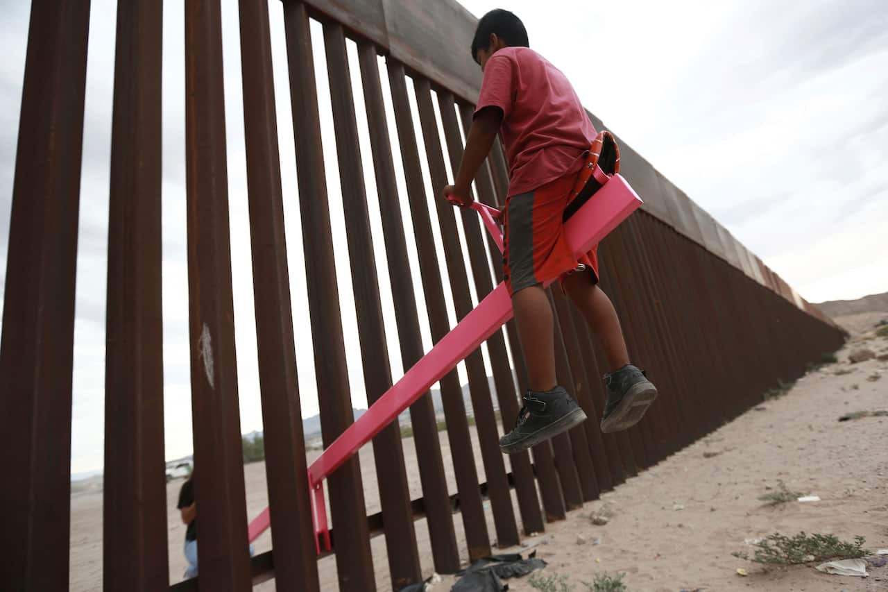 A kid plays n a seesaw installed between the steel fence that divides Mexico from the United States.