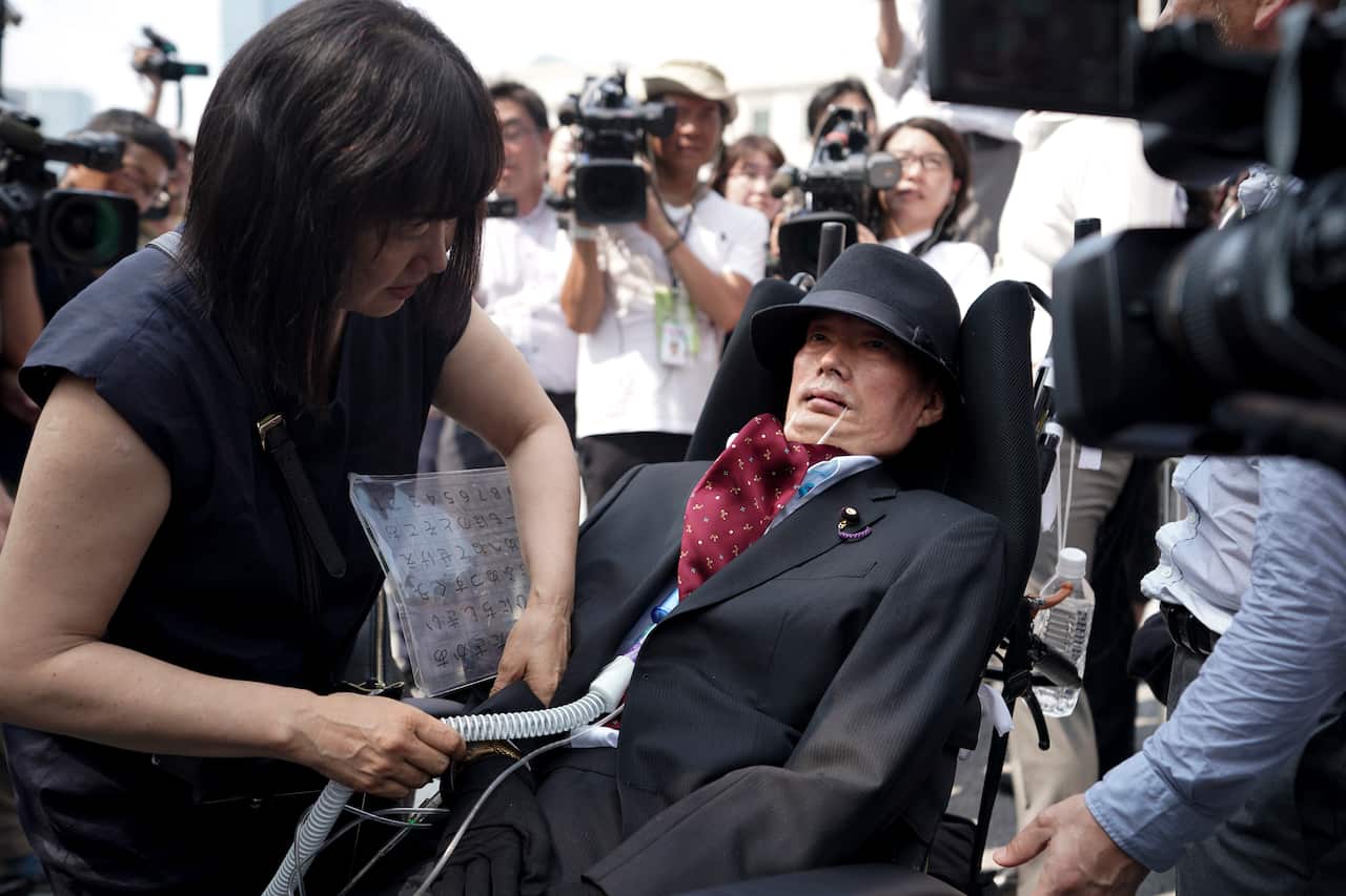 Yasuhiko Funago sits in his wheelchair as he is assisted to prepare to enter the front entrance of the parliament building in Tokyo, Japan.