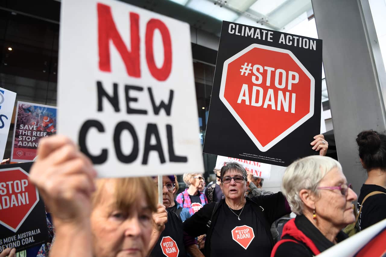Anti-Adani protesters hold placards outside the offices of engineering and construction company GHD in Brisbane, Thursday, August 1, 2019. (AAP Image/Dan Peled) NO ARCHIVING