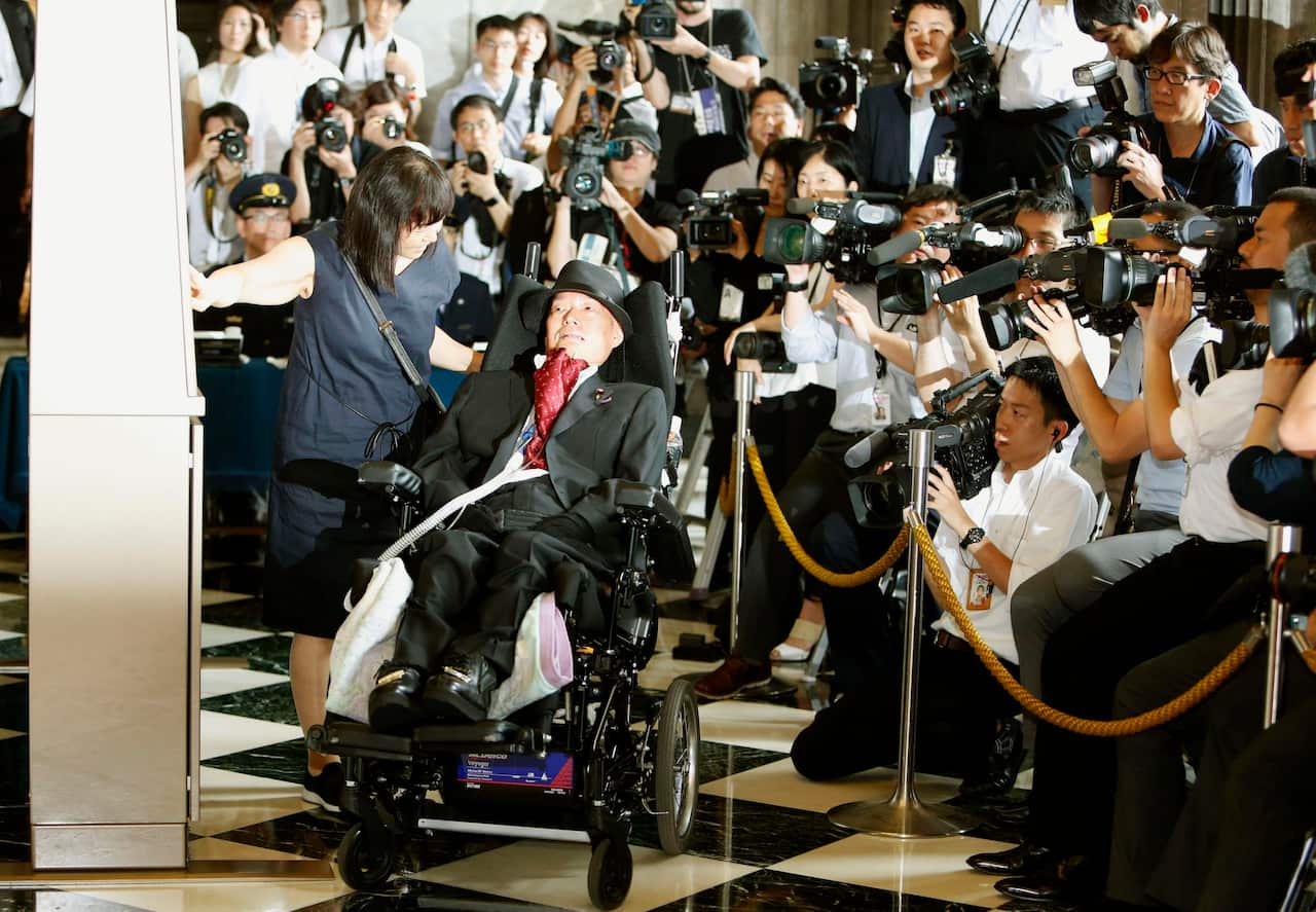 Newly elected lawmaker Yasuhiko Funago, watches on as his aide presses a button on the attendance board at the parliament building in Tokyo.